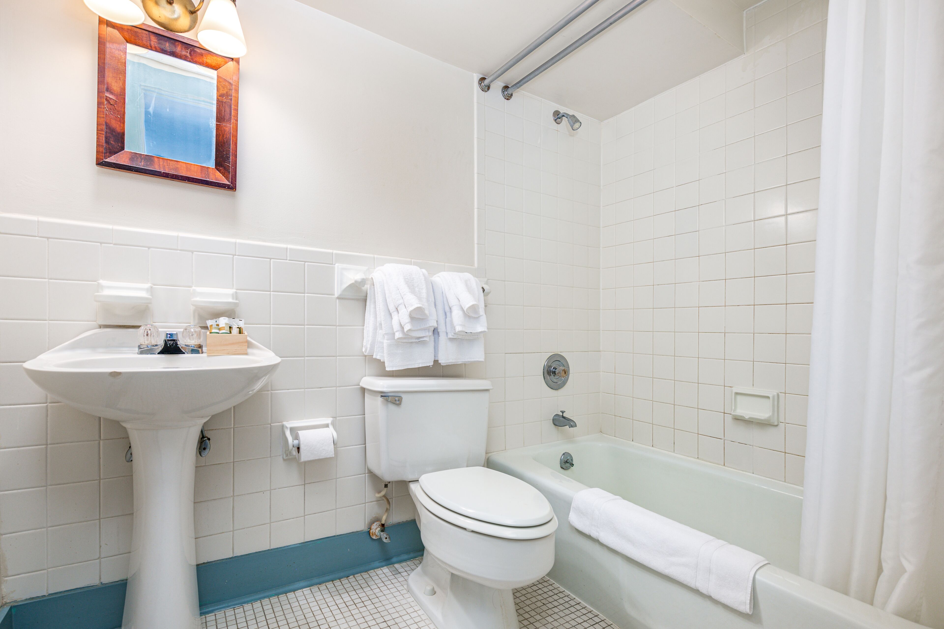 A bathroom with a pedestal sink, toilet, bathtub, and a shower curtain.