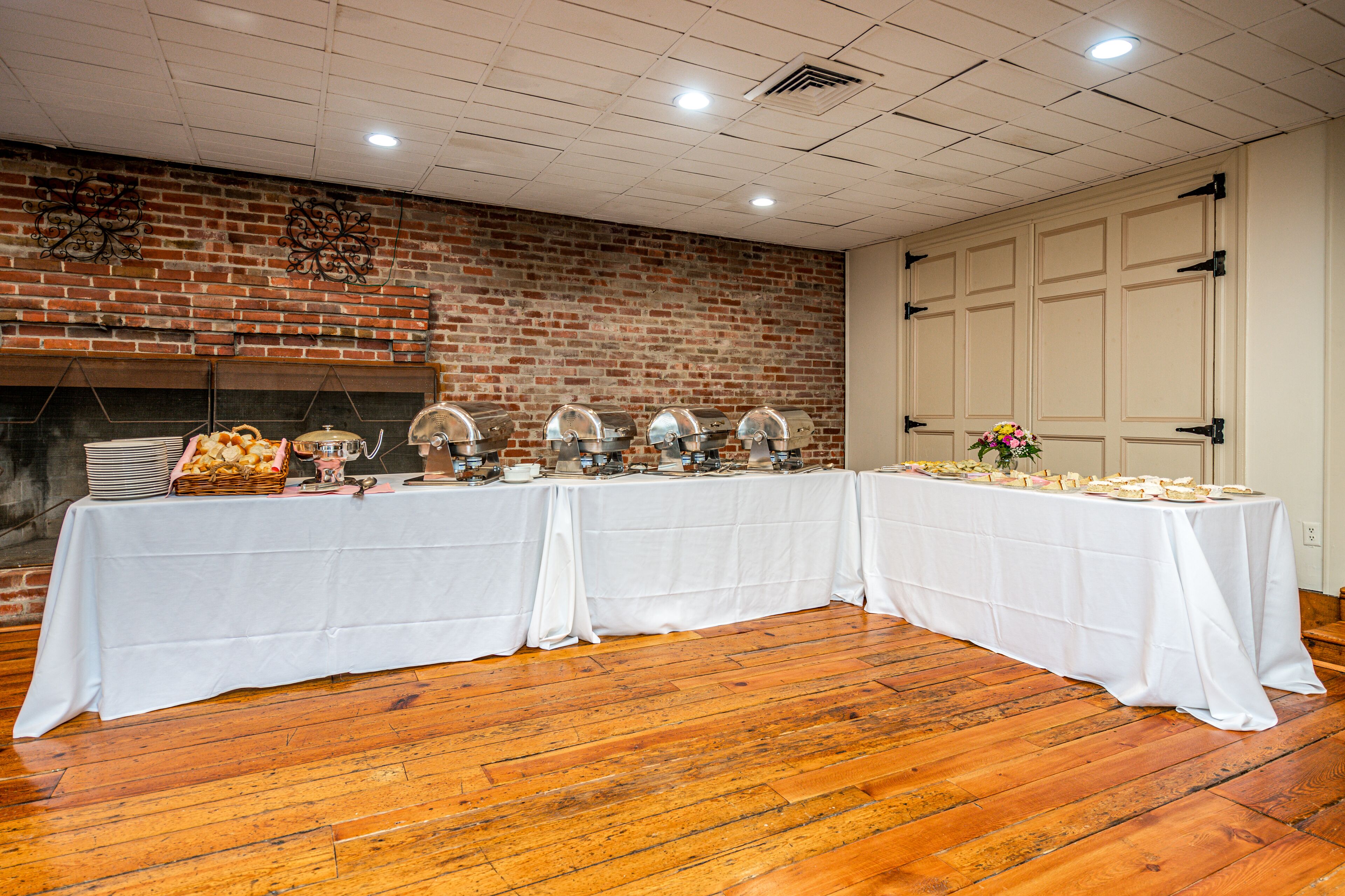 A buffet setup with a brick wall and wooden flooring.