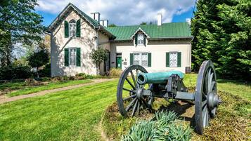Una casa histórica con techo verde y un gran cañón en el jardín delantero.
