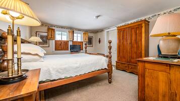 Un dormitorio con una cama de madera con dosel, un armario de madera y un escritorio con lámpara.
