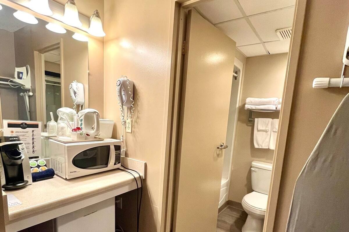 A hotel bathroom with a vanity, hairdryer, and toilet.