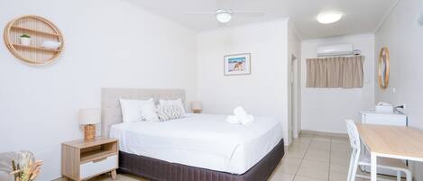 A hotel room with a bed, bedside table, lamp, and a small seating area with a table and chairs.
