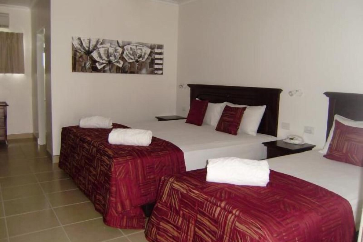 Habitación de hotel con dos camas, un ventilador de techo y un cuadro en la pared.