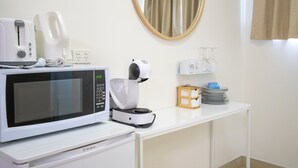Una kitchenette equipada con microondas, tostadora, cafetera y un refrigerador pequeño.