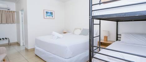 Habitación con literas, ventilador de techo, mesita de noche con lámpara y un cuadro en la pared.