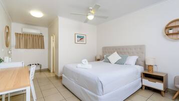 A neatly arranged hotel room with a bed, bedside table, and a small desk with a chair.