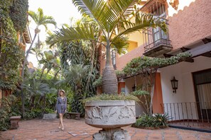 A courtyard with a central planter, surrounding buildings, and a person. - Hostería Las Quintas Hotel (Cuernavaca)