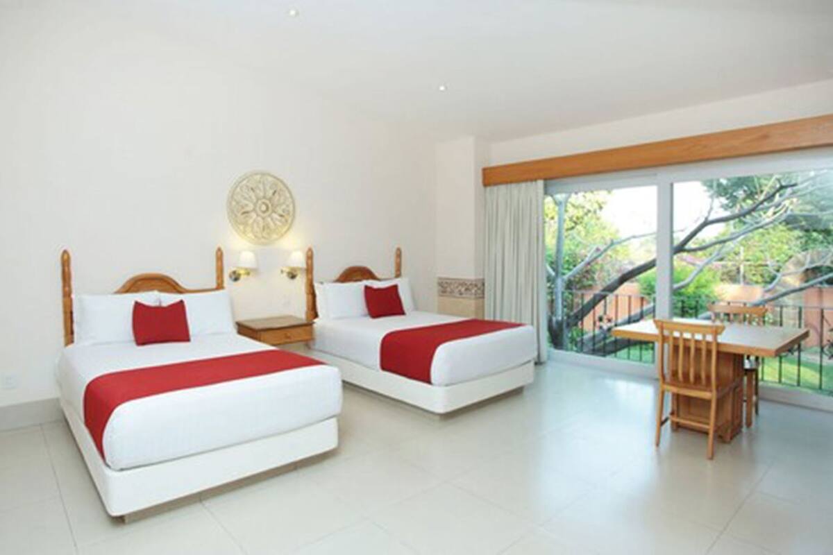 Habitación de hotel con dos camas, un balcón y una zona de comedor.