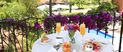 A round table with breakfast items, a glass of orange juice, and a vase of flowers.