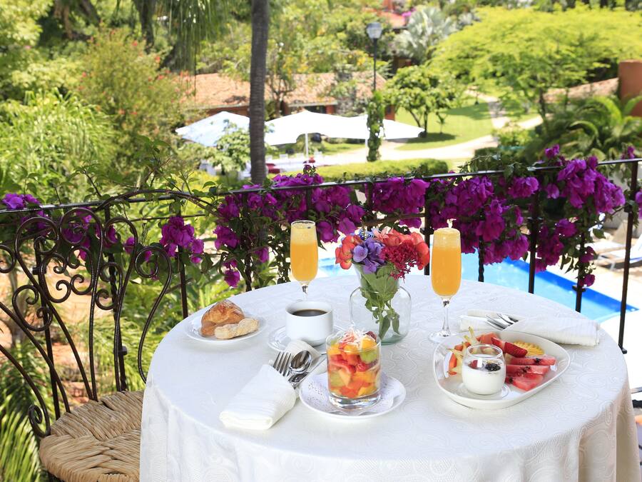 A round table with breakfast items, a glass of orange juice, and a vase of flowers.