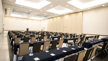 A conference room with rows of tables and chairs, equipped with water bottles and name cards.
