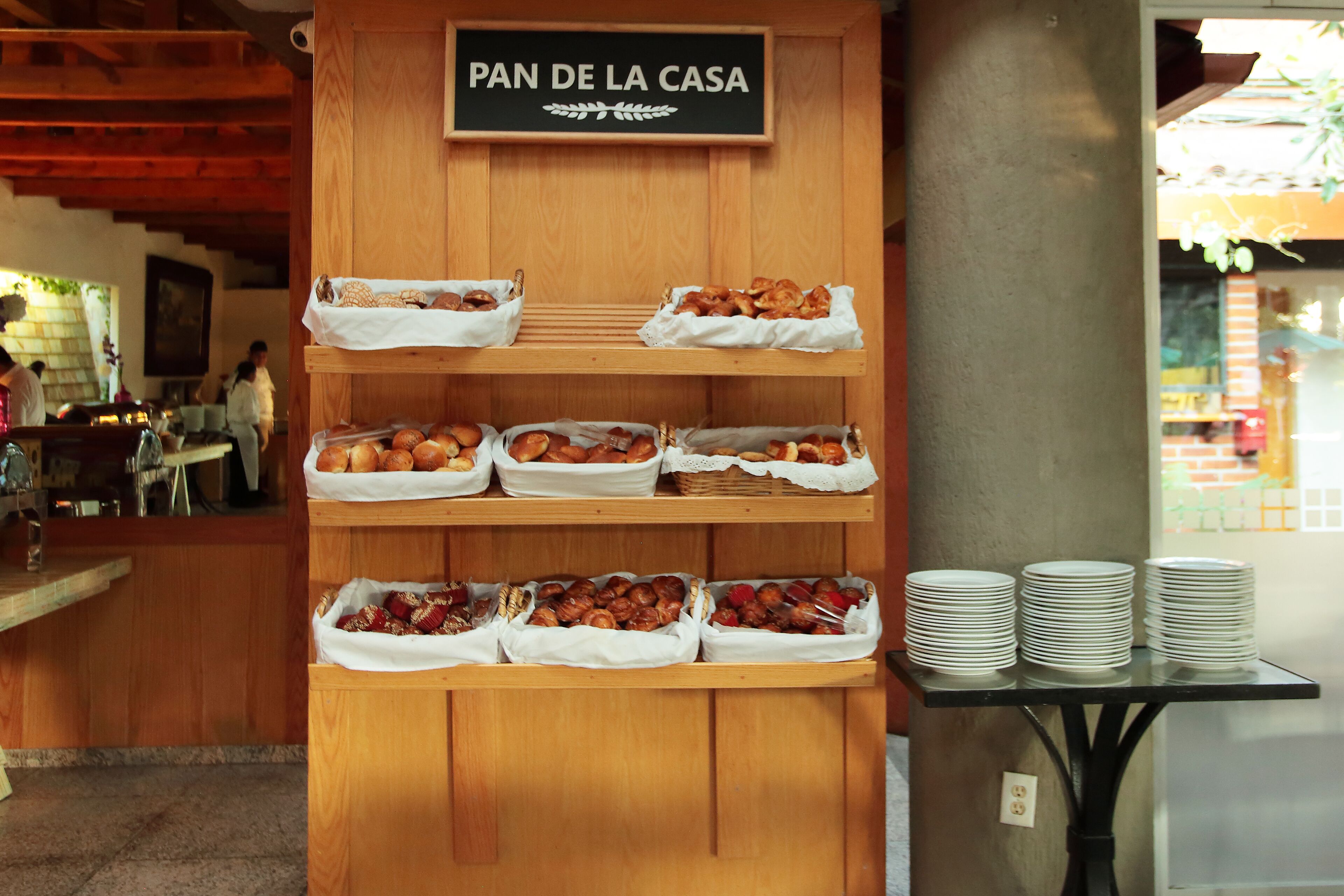 A breakfast buffet with various pastries and bread displayed on wooden shelves.