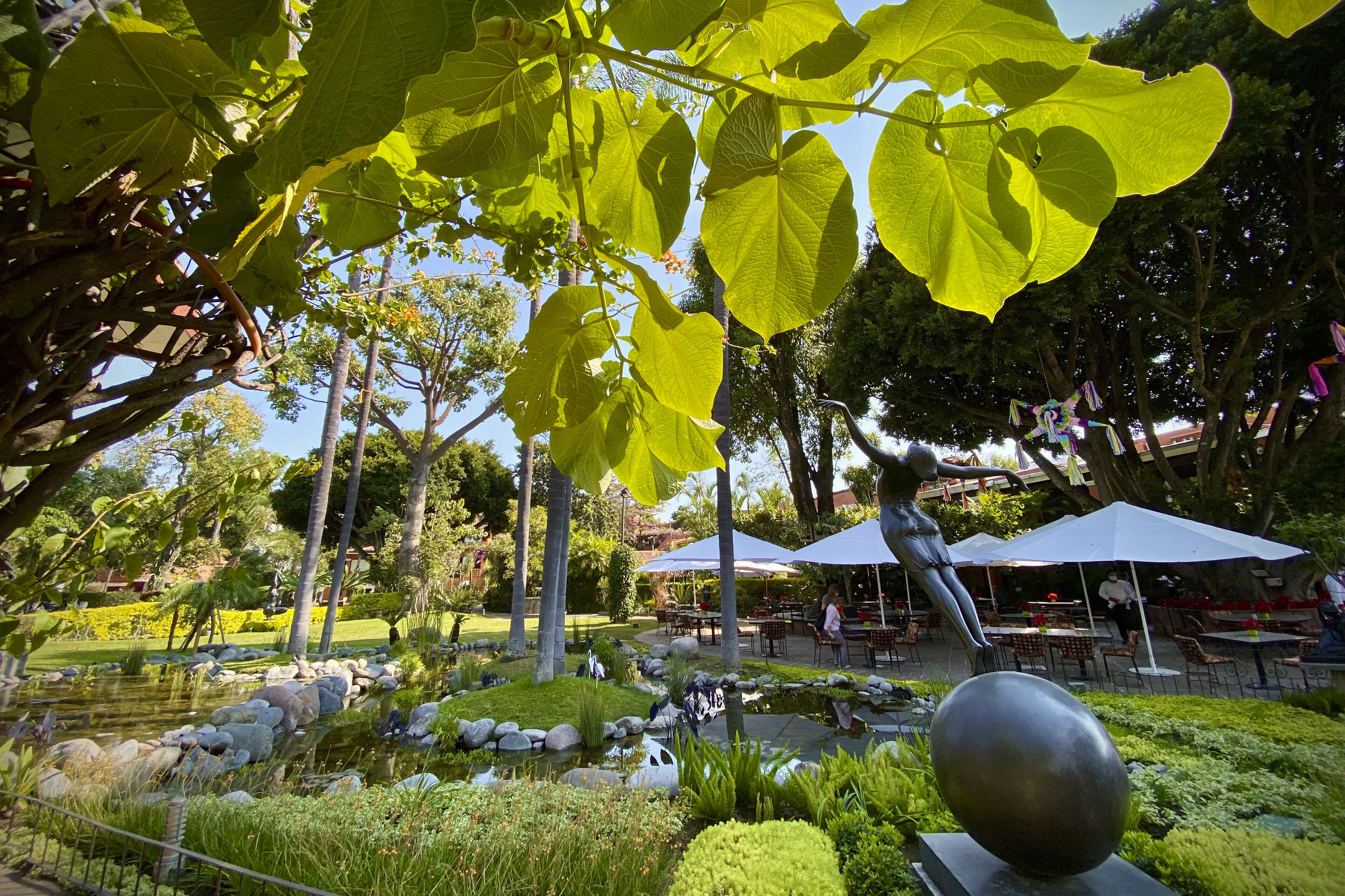 A garden with a pond, seating areas, and a statue.