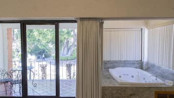 A bathroom with a large bathtub, a sliding glass door leading to an outdoor area with a patio and chairs.