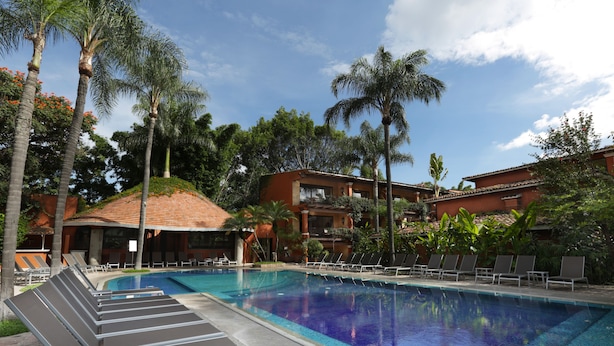 Una piscina con sillones de descanso y palmeras.
