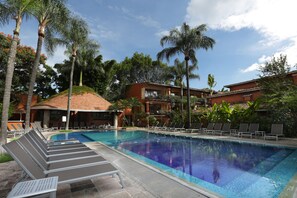 A swimming pool with lounge chairs and palm trees. - Hostería Las Quintas Hotel (Cuernavaca)