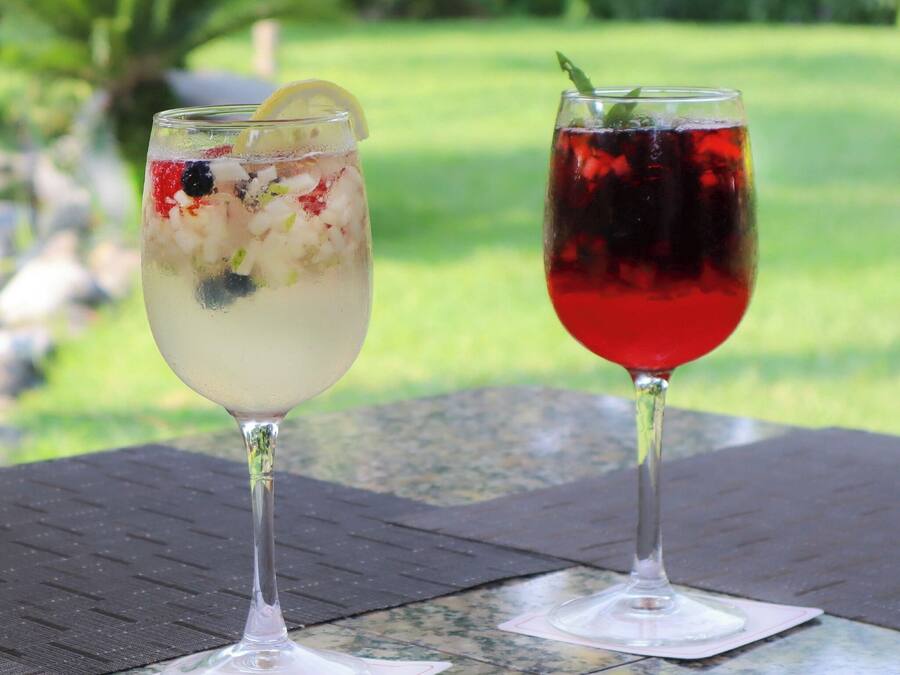Duas bebidas sobre uma mesa, com vista para uma paisagem verde.