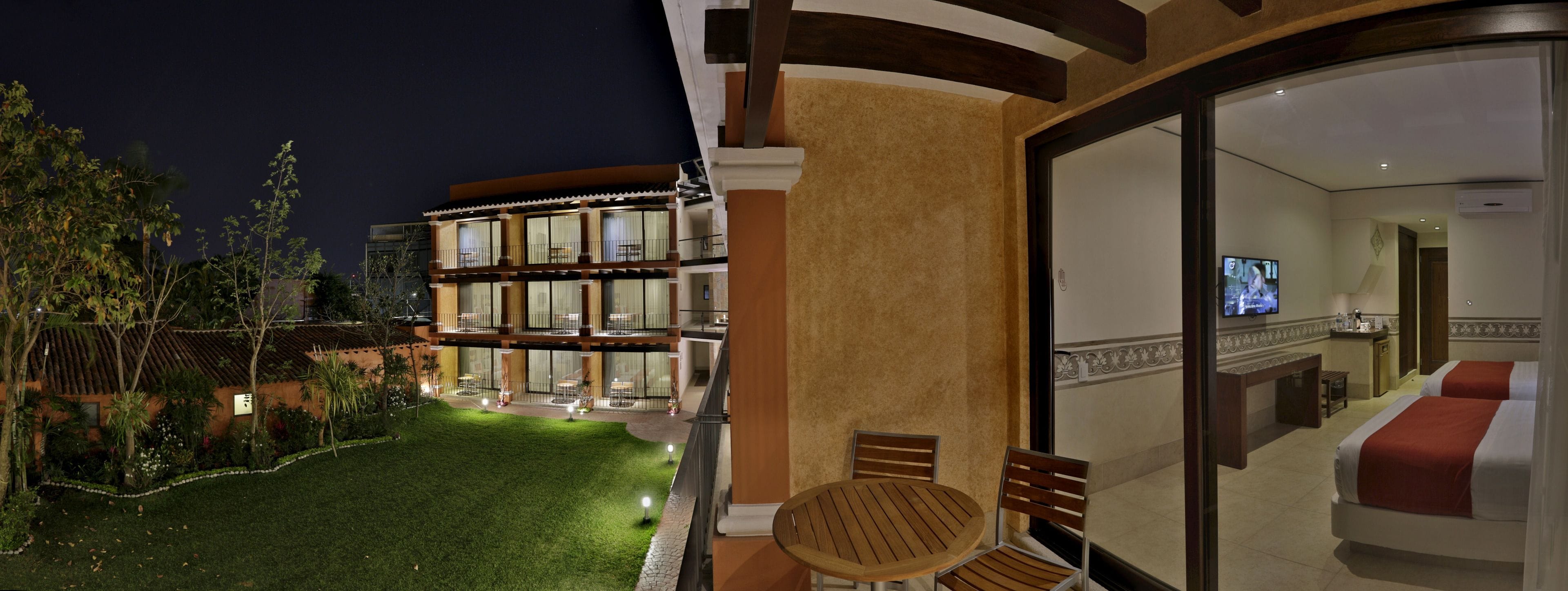 Habitación de hotel con balcón, televisión y vistas al jardín.