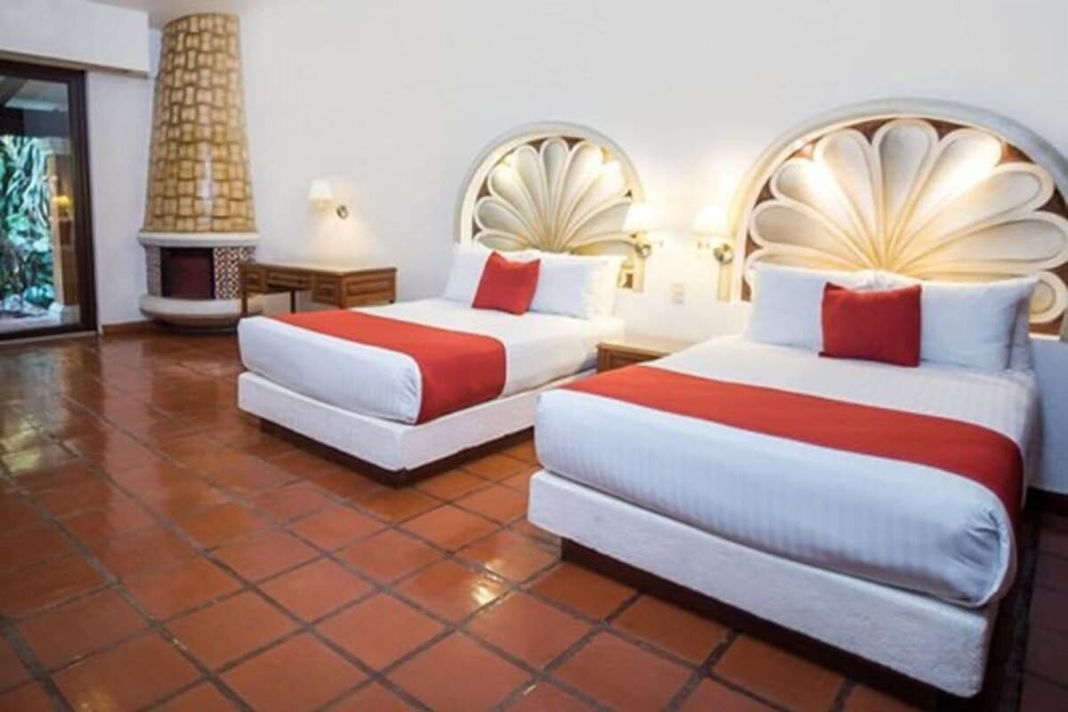 Una habitación de hotel con dos camas, chimenea y vistas al exterior.