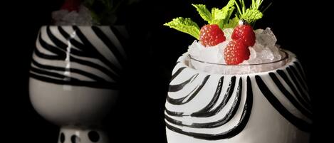 Two decorative vases with black and white patterns, each containing ice, strawberries, and mint leaves.