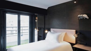 A hotel room with a large bed, a desk, a chair, a wall-mounted lamp, and a polar bear sculpture. - Tribe Paris Batignolles (Paris)