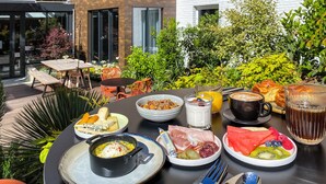 An outdoor dining area with a variety of breakfast items including fruits, cheeses, meats, and beverages. - Tribe Paris Batignolles (Paris)