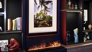 A framed picture of palm trees, a bookshelf with books, a vase, and a sculpture. - Tribe Paris Batignolles (Paris)