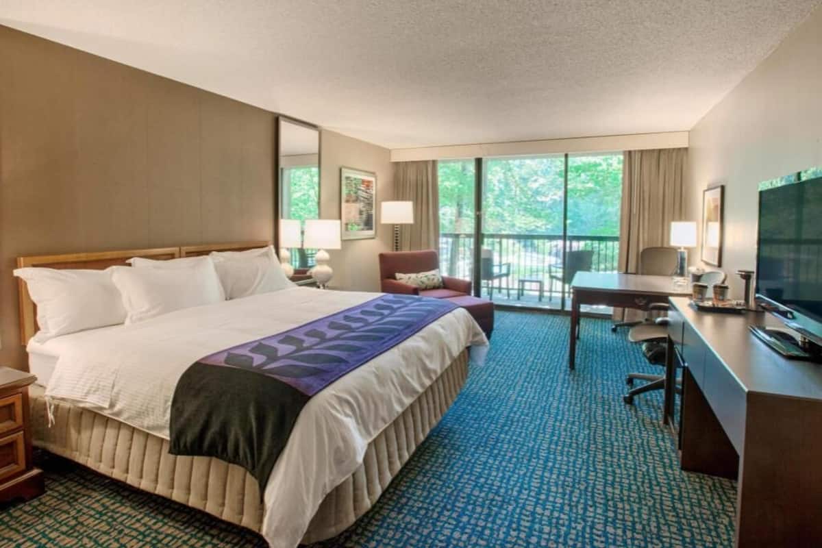 Una habitación de hotel con una cama grande, un escritorio, una silla y un televisor.