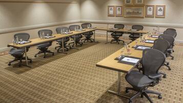 A conference room with long tables, chairs, and framed pictures on the wall.