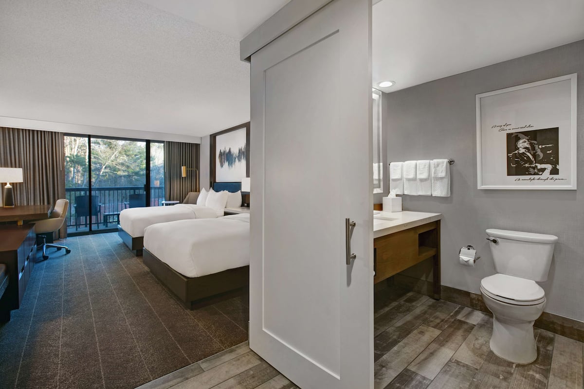 Habitación de hotel con cama, escritorio, silla y baño con inodoro y lavamanos.