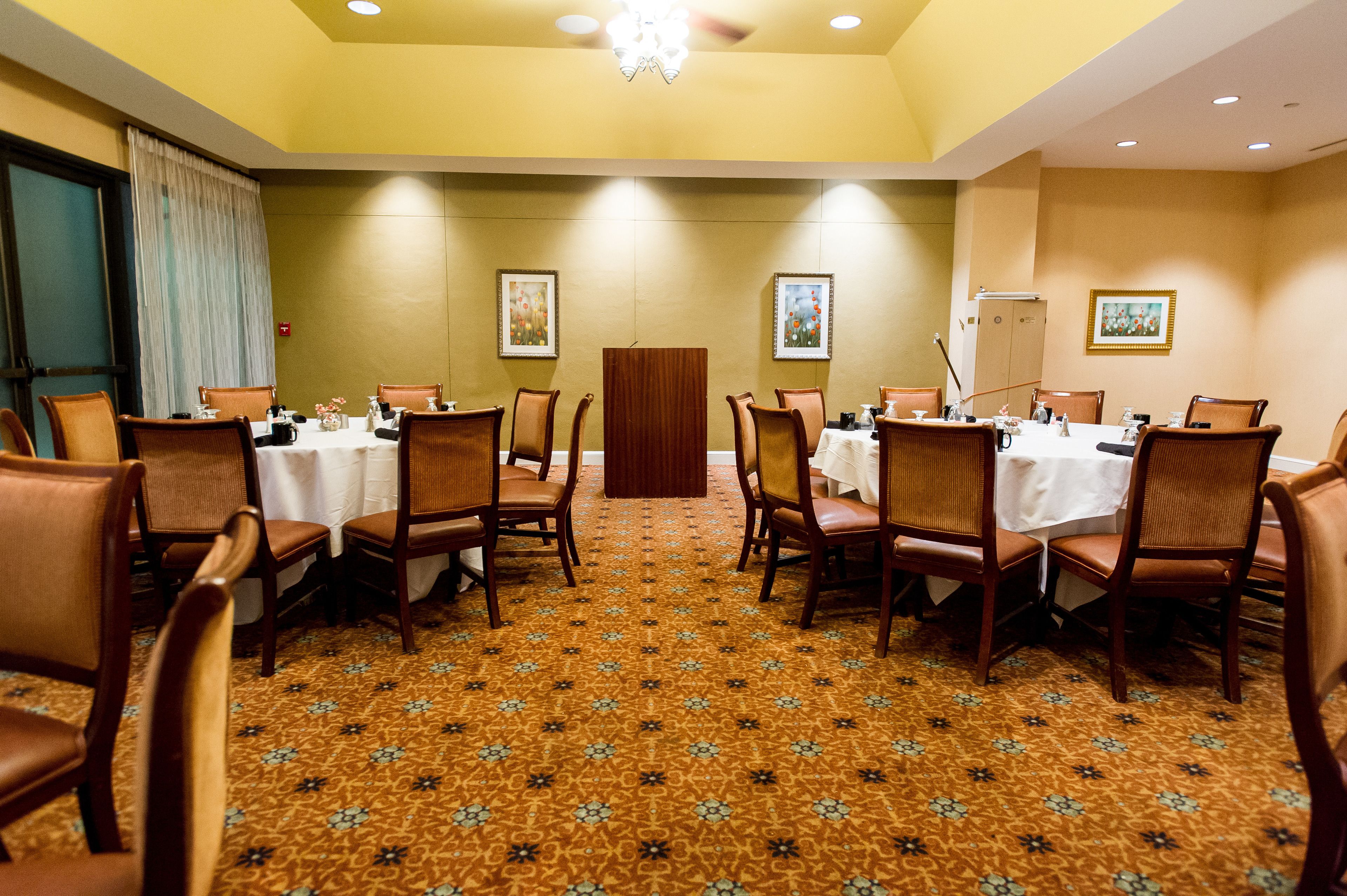 A conference room with a patterned carpet, wooden chairs, and tables set for meetings.