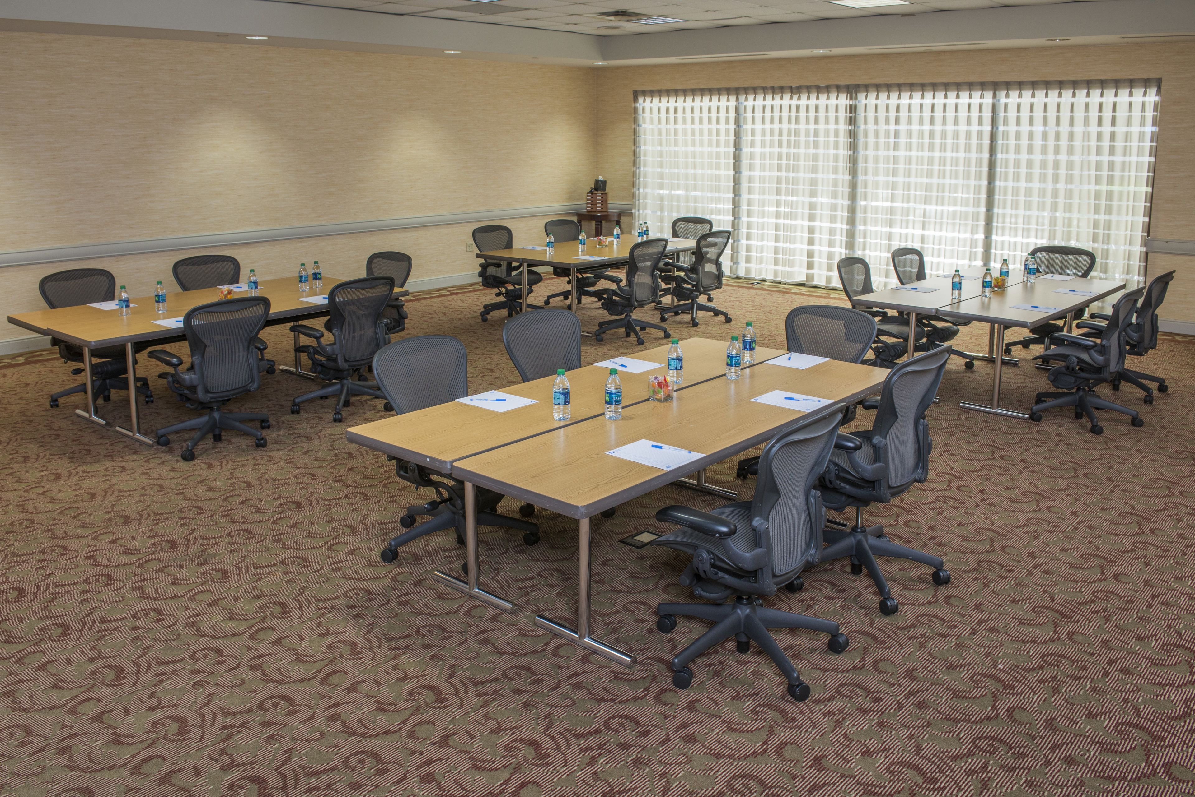 A conference room with multiple tables, chairs, and water bottles.