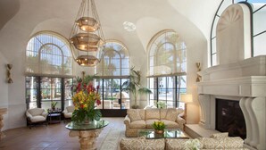 A spacious lobby with a fireplace, comfortable seating, and large windows. - Santa Barbara Inn (Santa Barbara)