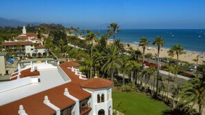 A coastal view with a beach, palm trees, and a white building with a red roof. - Santa Barbara Inn (Santa Barbara)