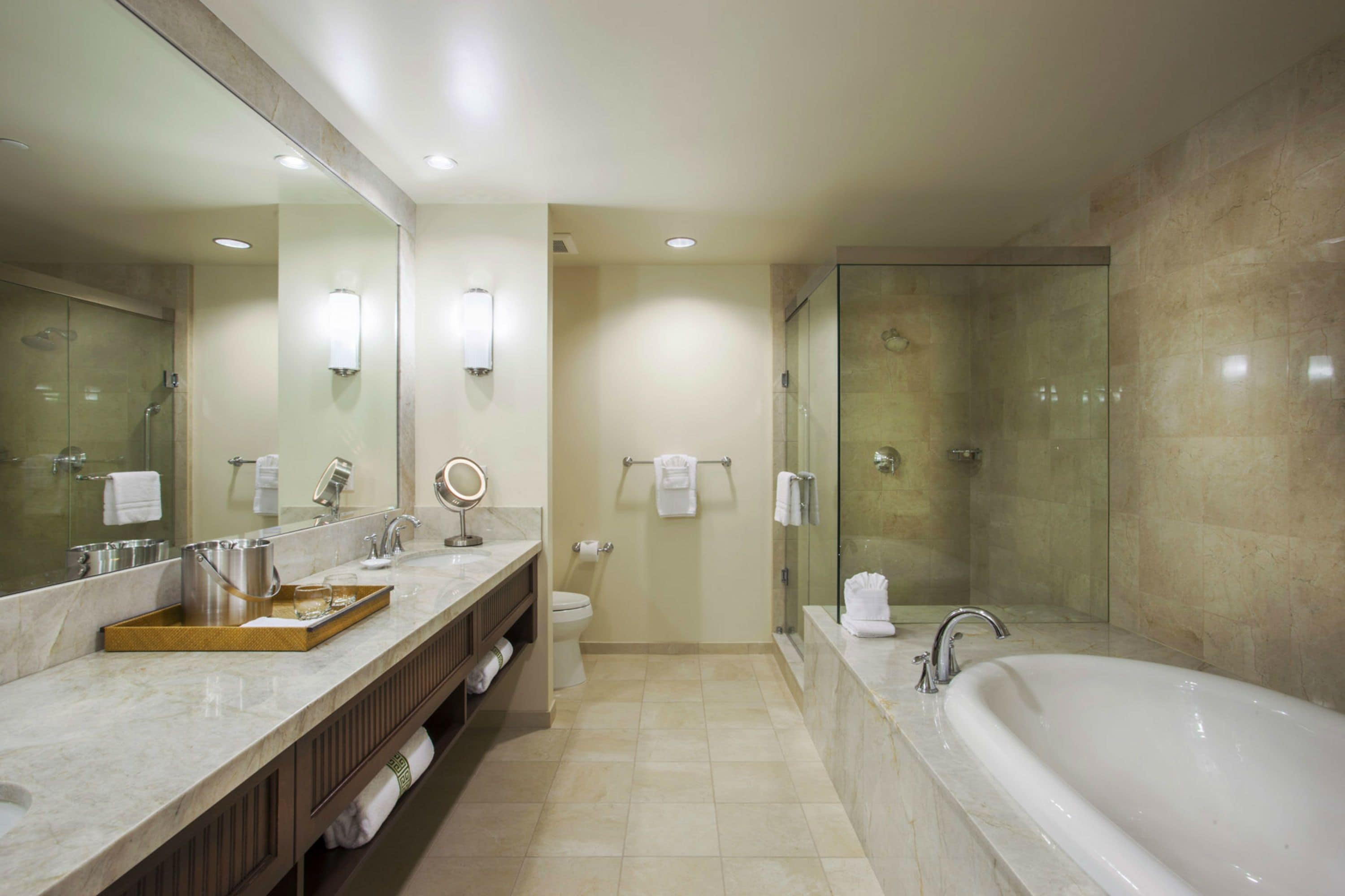 A modern bathroom with a large mirror, a bathtub, and a glass-enclosed shower.
