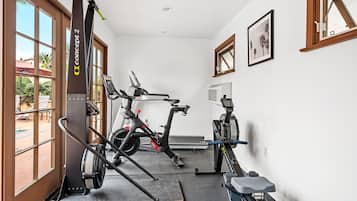A home gym with stationary bikes, a treadmill, and a rowing machine.