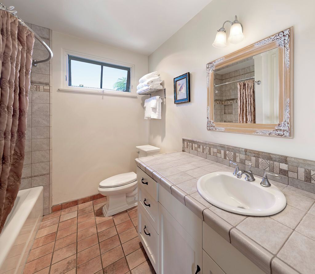 A bathroom with a bathtub, toilet, sink, and a window.