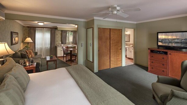 A hotel room with a bed, a desk, a television, and a dining area. - Brisas del Mar, Inn at the Beach (Santa Barbara)