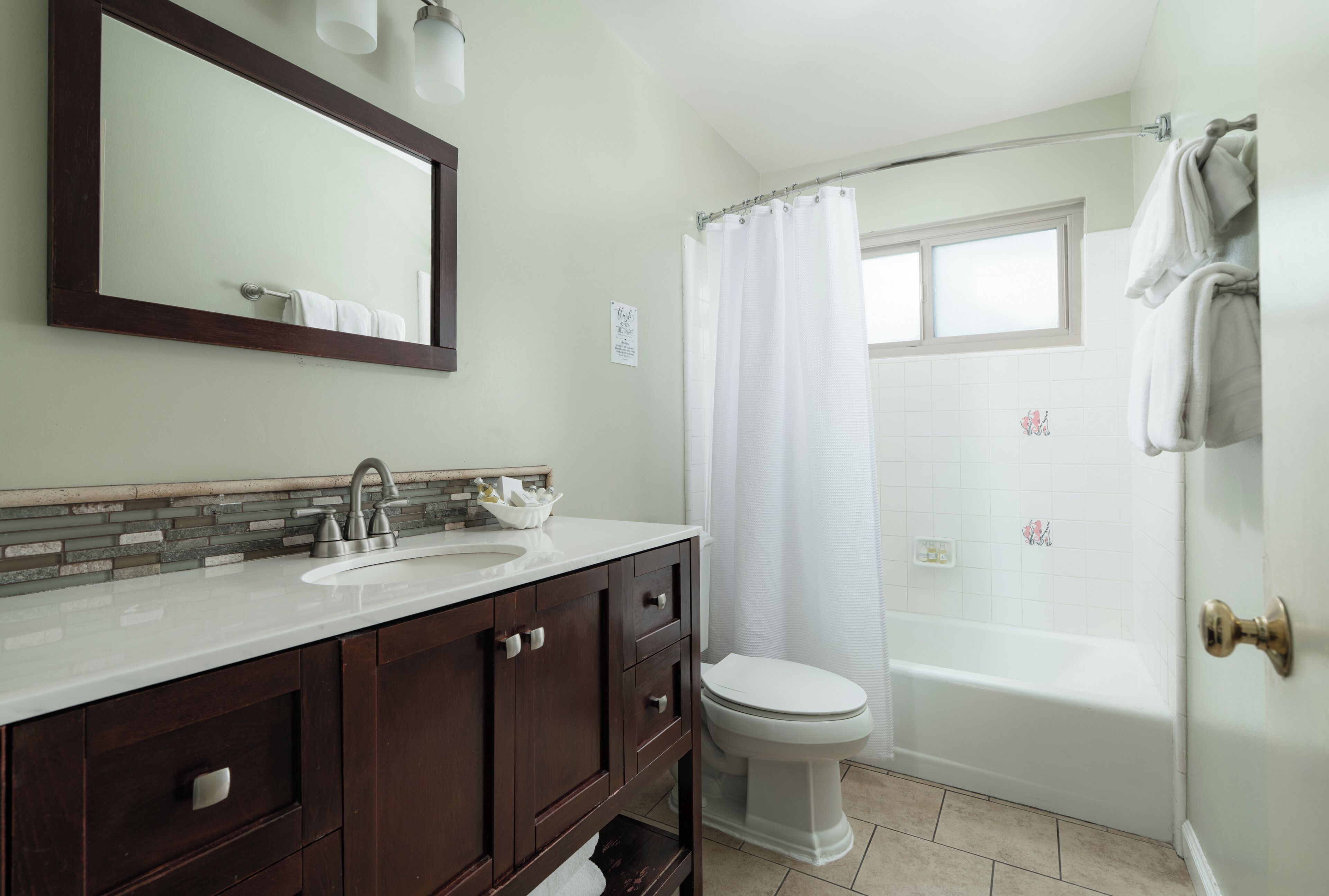 A bathroom with a sink, mirror, toilet, and bathtub.