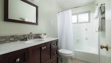 A bathroom with a sink, mirror, toilet, and bathtub.