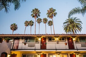 A hotel with multiple balconies, each with a railing and potted plants.