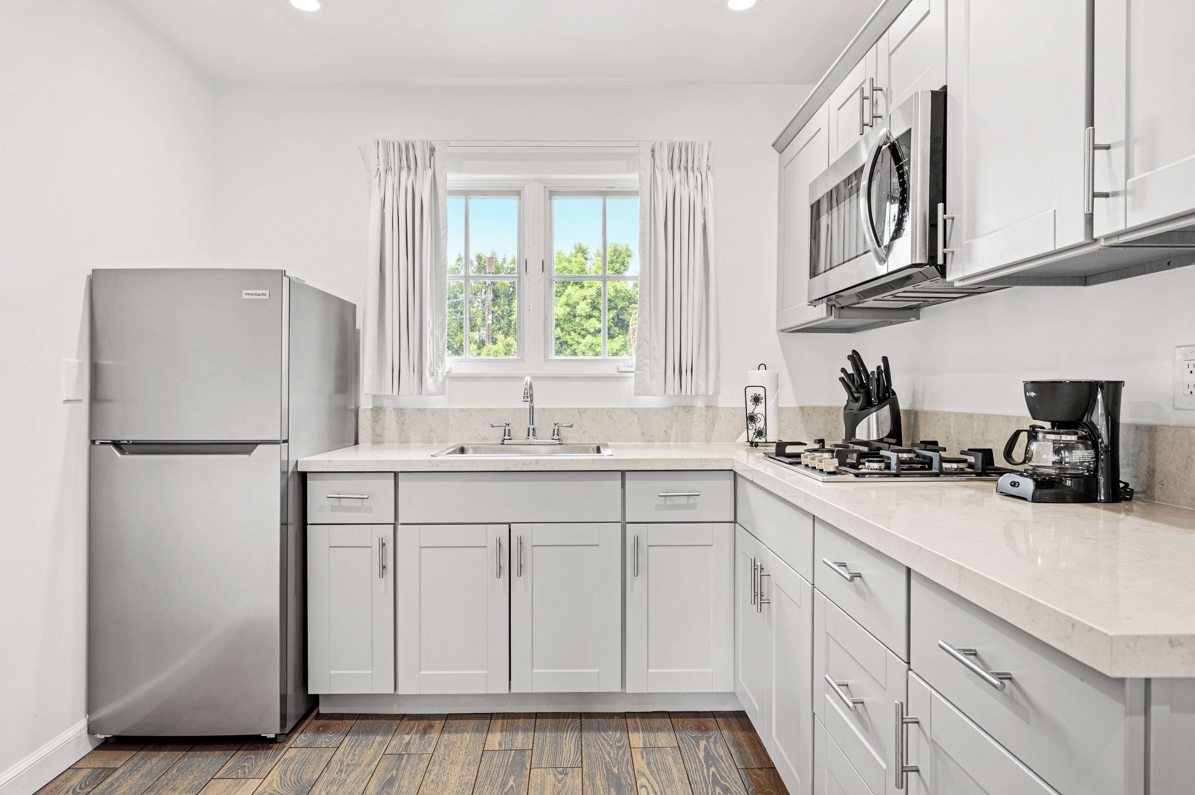 A modern kitchen with a refrigerator, sink, microwave, and stove.