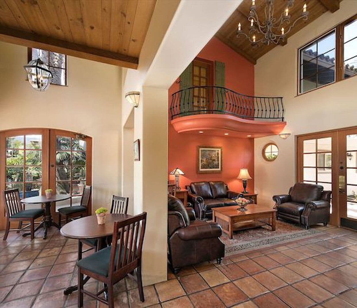 A spacious living area with a dining table, multiple seating options, a fireplace, and a balcony with a railing.
