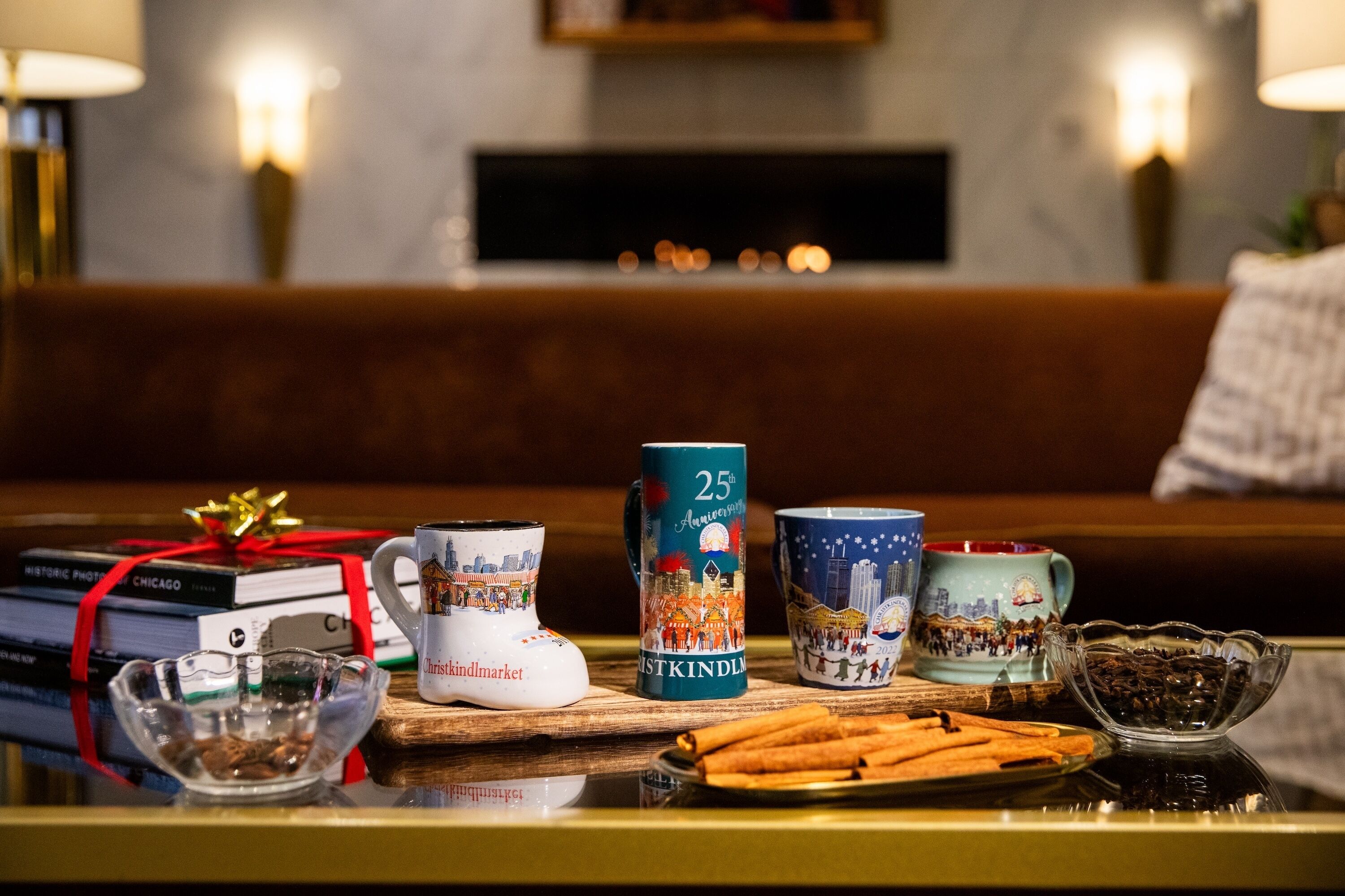 A table with books, mugs, a glass bowl, and cinnamon sticks.