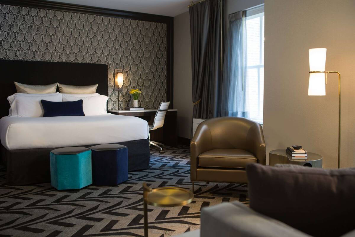 Een hotelkamer met een groot bed, een bureau, een stoel en een lamp.