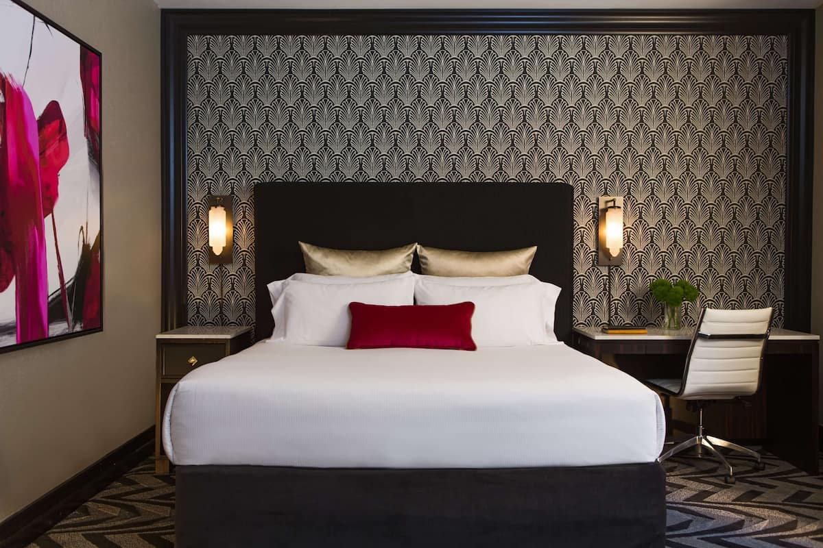 Een hotelkamer met een groot bed, twee nachtkastjes, een bureau en een stoel.