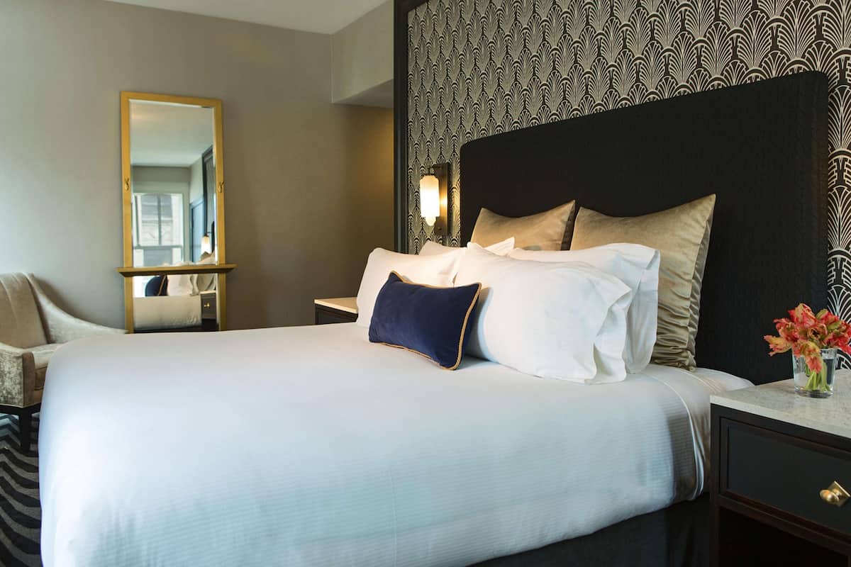 Hotelkamer met een groot bed, nachtkastje, spiegel en een wand met behang.