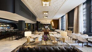 Un amplio vestíbulo de hotel con zona de bar, mesas de comedor y un área de estar central.