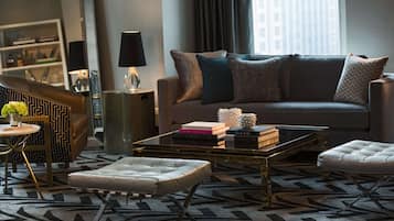 A modern living room with a sofa, ottoman, coffee table, and patterned rug.