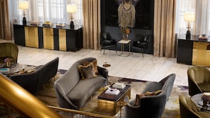 Un vestíbulo espacioso con una imponente escalera, un cuadro abstracto de gran tamaño y una zona de estar con muebles modernos.